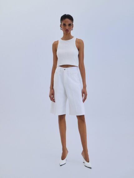 Γυναίκες που φορούν White Denim Bermuda από Combos, ένα κομψό λευκό τζιν σορτς για την καλοκαιρινή σεζόν.